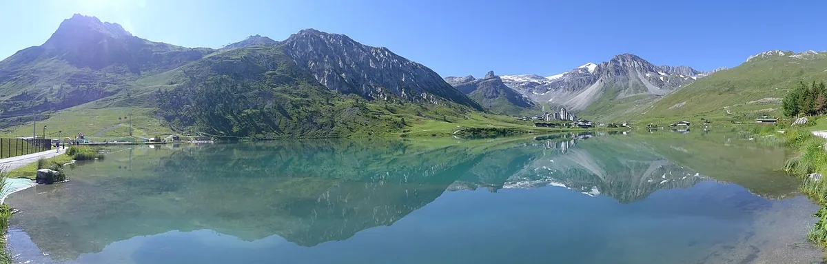 Panorama estivo del Lac de Tignes e delle montagne circostanti, verso sud-est (2018). Immagine generale di Tignes, non del singolo settore di ritiro o negozio di noleggio.